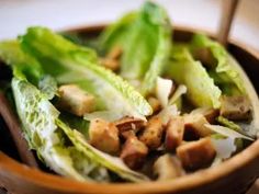 a wooden bowl filled with lettuce and meat