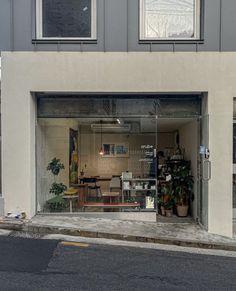 an open garage door with plants in the front and on the outside, next to a street