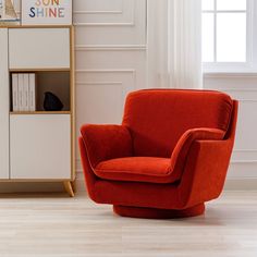 an orange chair sits in front of a bookcase and window with white drapes