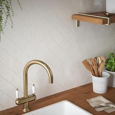 a kitchen sink with brass faucet and wooden cutting board on the countertop