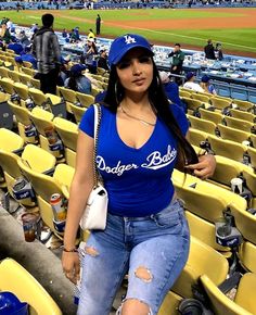 a woman is sitting in the stands at a baseball game wearing ripped jeans and a dodgers t - shirt