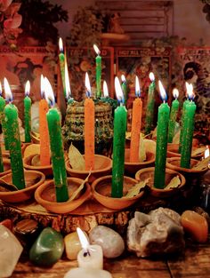 many candles are lit in the middle of a table with rocks and stones around it