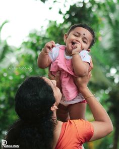 a woman holding a baby up to her face while another person holds the child in front of her