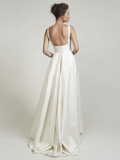 the back of a woman in a white wedding dress, with her hands on her hips