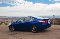 a blue car parked on the side of a road in front of a mountain range