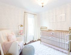 a baby's room with a white crib, pink and gold decor and a chandelier