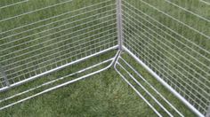 a close up of a metal fence with grass in the background