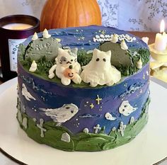 there is a cake decorated with dogs and cats on the table next to a candle