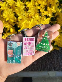 three different key chains are held in front of some flowers and yellow flowers with the words friends with us written on them