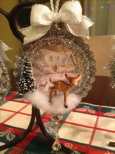 a glass ornament with a deer in the middle and snow around it on a table