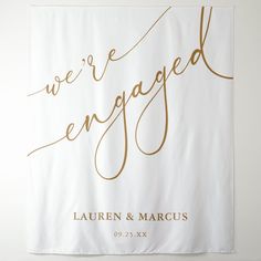 we're engaged banner with gold foil lettering on white paper, hanging from the wall