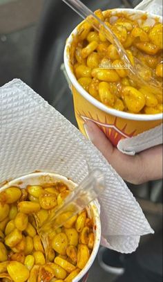 two paper cups filled with yellow food on top of a table