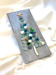 a christmas tree made out of seashells and glass beads on a white sheet