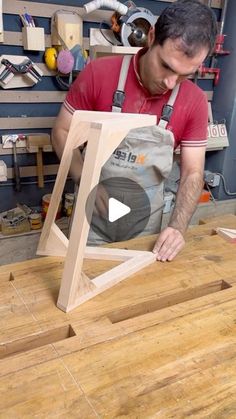 a man working on a piece of wood in his shop with the help of a video