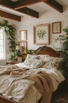 an unmade bed in a bedroom with plants on the wall and pictures above it