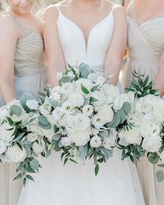 the bridesmaids are holding their bouquets with white flowers and greenery on them