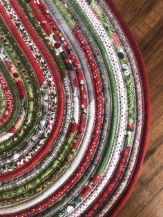 a close up of a circular quilt on a wooden floor with red, green and white fabric