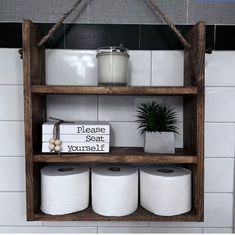 a bathroom shelf with toilet paper and a potted plant