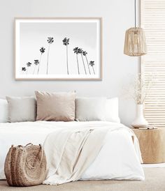 a bed with white sheets and pillows on top of it next to a wall mounted art piece