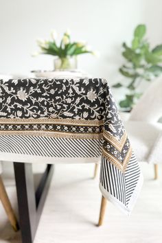 a black and white table cloth on top of a wooden table next to a potted plant