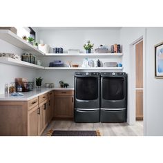 the front load washer and dryer in this kitchen are both black with stainless steel trim