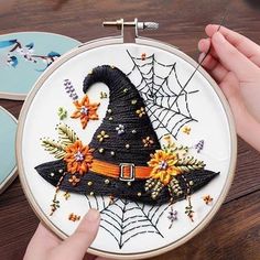 someone is stitching a witch's hat on a hoop with spider webs