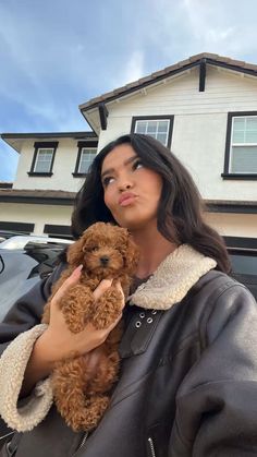 a woman holding a brown dog in front of a house