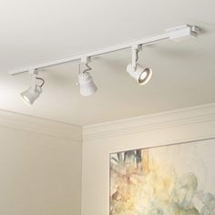 three lights are hanging from the ceiling in a room with a painting on the wall