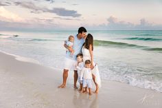 a family standing on the beach in front of the ocean