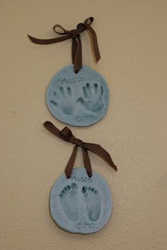 two hand and foot prints are hanging on the wall next to each other with brown ribbon