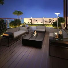 an outdoor living area with couches, tables and lamps on the deck at night