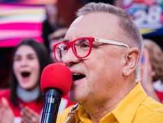 an older man with glasses singing into a microphone