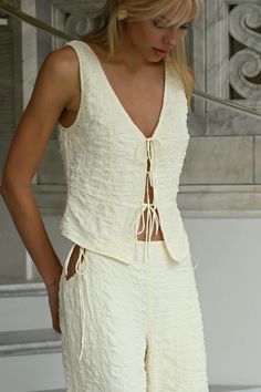 Crafted with lightweight fabric, the Tatum Tie Vest top offers a delicate sleeveless blouse look with a textured, breathable construction. Reversible for a tie-front or high-neck silhouette. Delicate tie closures Crinkled bubble texture Ivory buttercream coloring Wear with our Jai Bubble Tie Pants in Buttercream Tank f Tie Front Vest, Hoi An Tailor, Bubble Texture, Tie Vest, Tie Pants, Tailored Clothes, Top Moda, Design Clothes, Front Tie Top