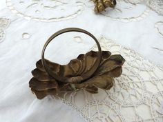 an antique brass flower ring on a white tablecloth with doily and laces