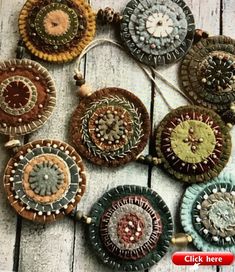 several circular pieces of fabric hanging on a wooden surface with beads and buttons attached to them