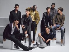 a group of young men sitting on top of a white bench next to each other