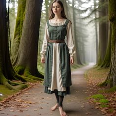 This stunning peasant dress for women will make you feel like you are a true medieval or Renaissance woman. This gown is made and designed with much historical work put into it, it has an overdress in a rich green color and an underdress in a cream color, thus making it look very timeless. The dress is rather plain but the cut will allow the wearer to represent a medieval peasant, a maidservant of the Renaissance or even a character from a fairytale. The long sleeves and the rather low neckline look authentic, and the material is comfortable for long wearing, which is essential in festival, reenactment, or cosplay activities. The dress is accompanied by a brown belt that pulls the waist, making it look more traditional. Ideal for those who would like to represent the ordinary life of histo 1400s Fashion Peasant, Elven Style Costume Dresses, Long Sleeve Fairycore Costume Dresses, Fairycore Dresses For Cosplay And Costume Parties, Fairycore Costume For Cosplay Events, Medieval Dresses For Cosplay With Historical Design, Medieval Historical Design Dresses For Cosplay, Fairycore Dress For Cosplay Events, Fairycore Cosplay Dress