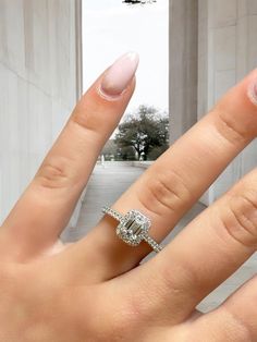 a close up of a person's hand with a ring on their finger and an arch in the background