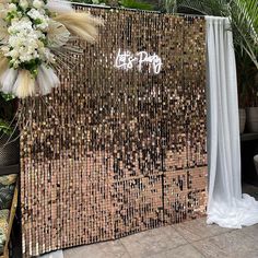 a gold sequin backdrop with white flowers and greenery on the side for a wedding ceremony