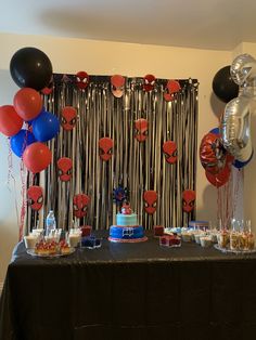 a table topped with cake and balloons in front of a wall covered in streamers