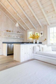 a white couch sitting in a living room next to a wooden wall and ceiling covered in wood planks