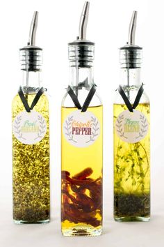 three bottles filled with different types of liquid and herbs in them on a white surface