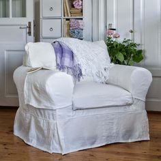 a white chair sitting on top of a hard wood floor next to a book shelf