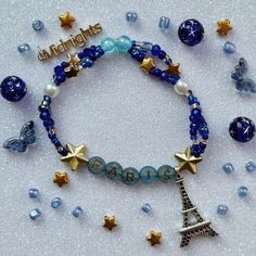 a bracelet with the eiffel tower, stars and beads on it that says paris