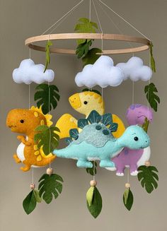 a mobile with different colored stuffed animals hanging from it's sides and green leaves