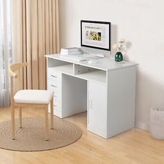 a white desk with a computer monitor and keyboard on it in front of a window