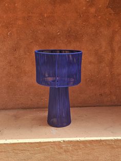 a blue vase sitting on top of a wooden table next to a brown stucco wall