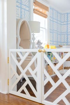 an open white gate in the middle of a room with blue walls and wooden floors