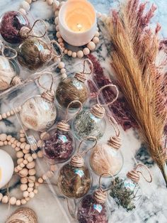 an assortment of ornaments and beads on a marble surface with a candle in the middle