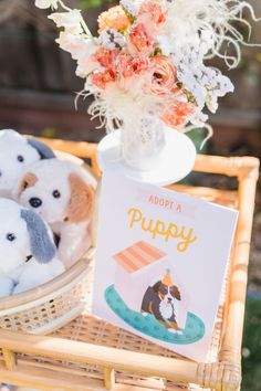 stuffed animals are sitting in a basket on a table with a book about a puppy